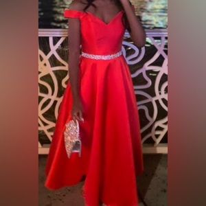 A red off the shoulder prom dress with a bedazzled torso all around.